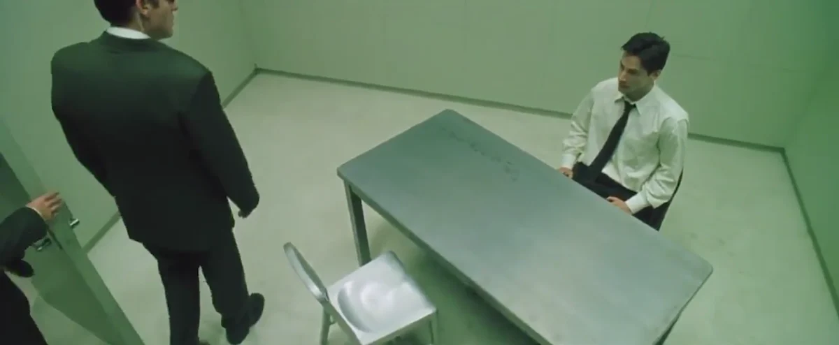 Análise de Matrix. Agente Smith encarando Thomas Anderson na sala de interrogatório em The Matrix.